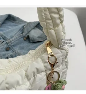 Detail of smooth gold zipper and floral charm on a white quilted cloud bag