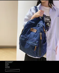 Detail of vintage navy denim backpack featuring leather pullers and brand patch