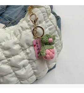 Detail of white quilted bubble bag with handmade crochet strawberry charm and pink tag