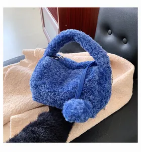 Detail of blue plush handbag featuring soft faux fur texture and matching pompom charm