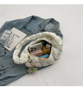 Top view of spacious white quilted cloud bag interior holding phone and cosmetics