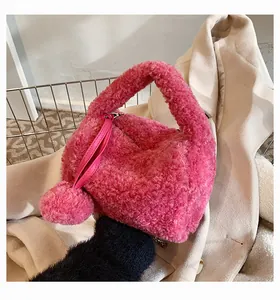 Close-up of pink fluffy plush handbag with pom-pom charm on cream coat background