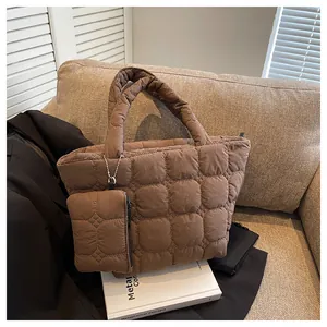 Detailed view of brown quilted puffer tote bag with matching pouch on a beige sofa