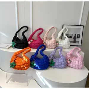 Collection of colorful quilted puffer bags with cute charms on a white display stand