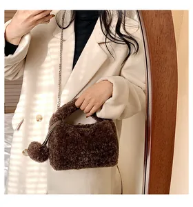 Detailed view of brown plush handbag with soft texture, metal chain, and pom-pom charm