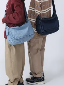 Large denim crossbody bag for students shown in light and dark blue on a model