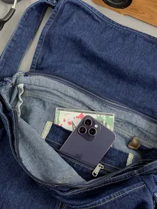 Large denim crossbody bag with inner zipper pocket shown from a top-down interior view