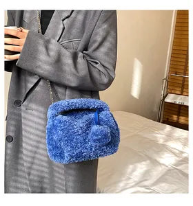 Detail of bright blue plush crossbody bag with silver chain strap and faux fur texture