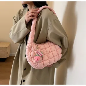 Pink quilted puffer shoulder bag with cute strawberry charm on a beige trench coat