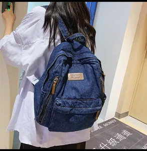 Detailed view of spacious denim backpack with vintage leather logo and strap details