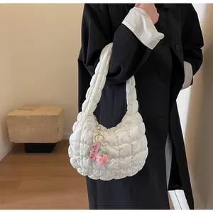 Detailed shot of white quilted puffy handbag with handmade strawberry charm on black coat