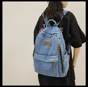 Detail view of large denim backpack showing leather logo patch and side pocket