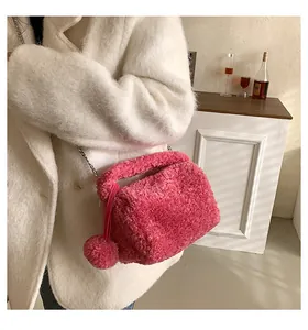 Close-up of rose pink plush crossbody bag with silver chain strap and pompom charm