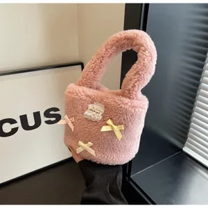 Detail of pink faux shearling bucket bag with lace patch and ribbon bow decoration