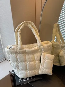 Chic quilted beige tote bag with matching coin purse on a stylish mirror surface