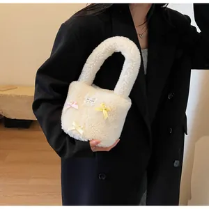 Close-up of white plush lamb wool bucket bag with colorful bow details on a model