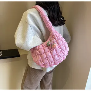Close-up of pink quilted cloud bag with puffy texture and knitted flower pendant