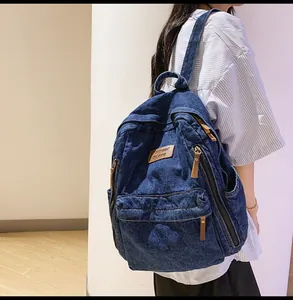 Detail of dark blue denim backpack featuring functional zipper pockets and street style