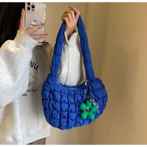 Close-up of blue quilted cloud bag with green flower charm and soft puffed handle