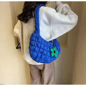 Close-up of blue ruched cloud bag featuring a vibrant green floral plush charm detail