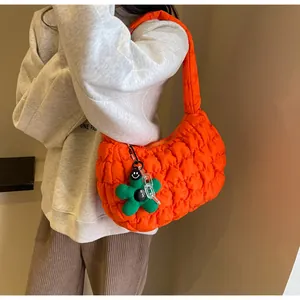 Detail of orange quilted puffy shoulder bag featuring a cute green flower charm