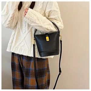 Detail der schwarzen Lederbeuteltasche mit Goldverschluss zu herbstlicher Strickware