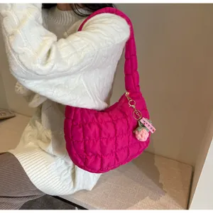 Detail of rose red quilted hobo bag with strawberry charm and golden metallic zipper