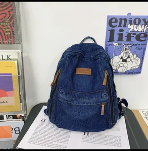 Detail of vintage navy denim backpack with brown leather patch and zip pockets