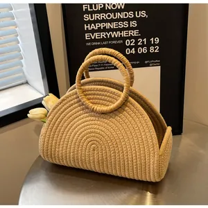 Detail einer halbrunden Stroh-Handtasche mit runden Griffen und Tulpendekoration