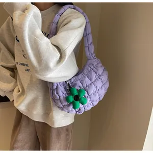 Close-up of lavender quilted shoulder bag featuring a decorative green floral pendant