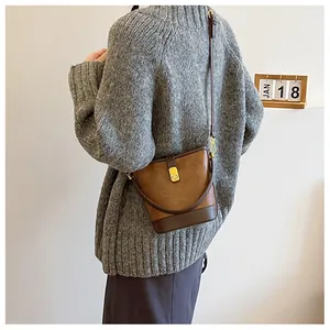 Nahaufnahme der braunen Retro-Beuteltasche mit Goldverschluss an einem Model