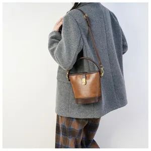 Detail der Retro-Bucket-Bag in Kontrastfarben mit goldenem Drehverschluss am Mantel