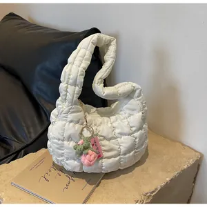 Detail of white quilted dumpling bag featuring a pink knitted strawberry charm