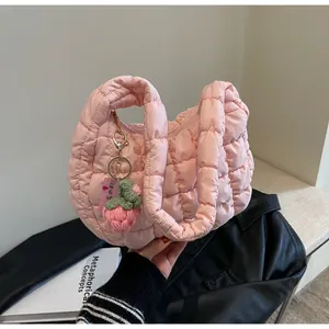 Detailed macro view of pink quilted bubble handbag featuring a strawberry crochet pendant