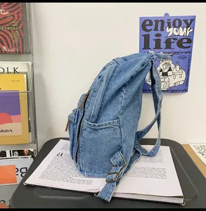 Detail of light blue denim backpack showing side pocket and vintage copper metal buckle