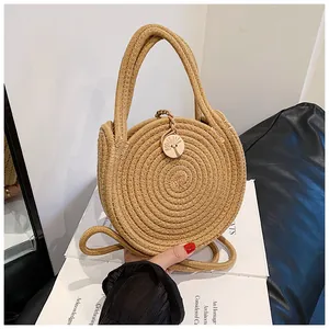 Détail d'un sac à main rond en paille avec tissage en spirale et boucle en bois gravé