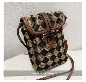 Close-up of brown checkerboard mini crossbody bag with leather strap and horn button