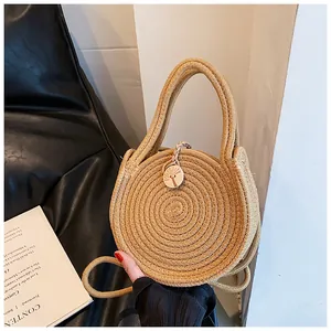 Détail d'un sac rond en paille tressée avec bouton en bois gravé d'un cocotier