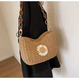 Detalle del bolso de paja tejida con flor de margarita blanca y cadena de resina