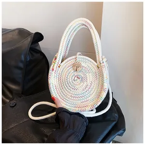 Détail d'un petit sac rond tressé blanc avec broderies colorées et bouton en bois gravé