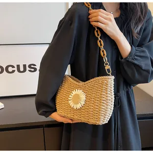 Detalle de bolso de paja tejido a mano con diseño de margarita y correa de cadena de ámbar