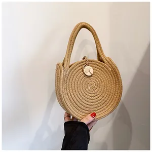 Détail d'un sac à main rond en paille avec texture tressée et bouton en bois fleuri