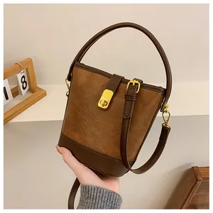 Detail einer braunen Vintage-Eimertasche aus Leder mit goldenen Beschlägen und Trageriemen-Design