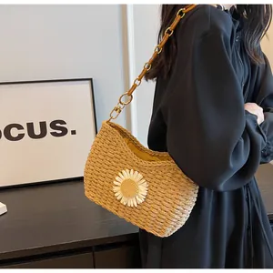 Detalle del bolso de hombro de paja tejida con margarita blanca y cadena de resina ámbar