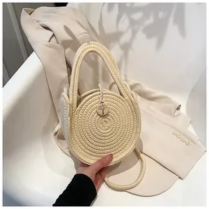 Vue détaillée du sac rond en paille avec texture spirale et bouton en bois gravé