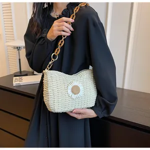Detalle del bolso de paja tejida con margarita blanca y cadena de acrílico ámbar