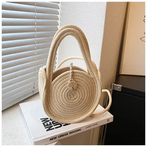 Détail du sac rond tressé crème avec emblème en bois et poignées circulaires