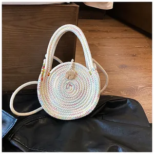 Détail du sac à main rond tissé avec des coutures en zigzag colorées et un bouton en bois