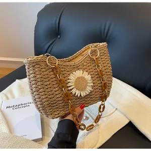 Detalle de bolso de paja trenzada con flor de margarita blanca y cadena de resina ámbar