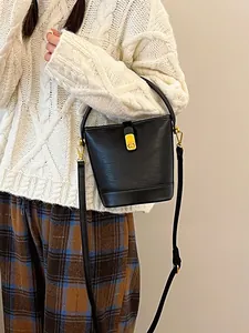 Retro schwarze Beuteltasche mit Goldbeschlägen an einem Modell mit weißem Pullover